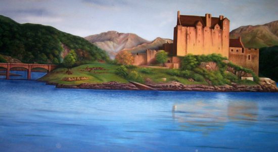 Medieval castle on an island with a stone bridge to the left, overlooking a calm blue lake.