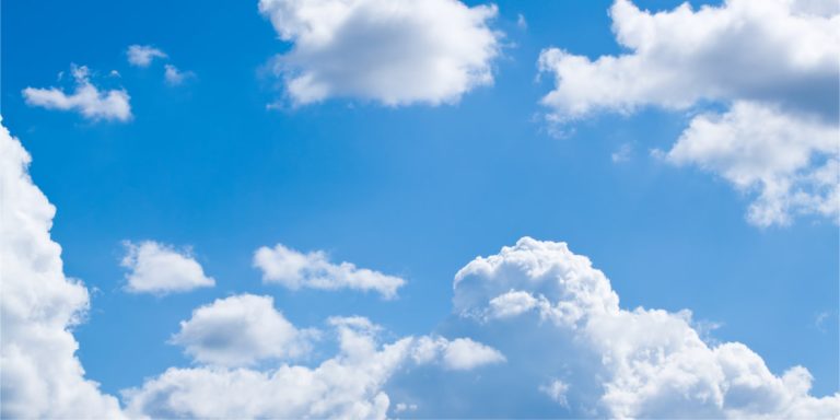 Bright blue sky with fluffy white clouds drifting across.
