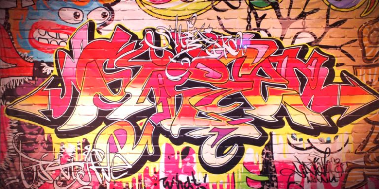 Vibrant graffiti mural with interwoven red, pink, and orange letters on a brick wall, outlined in black.