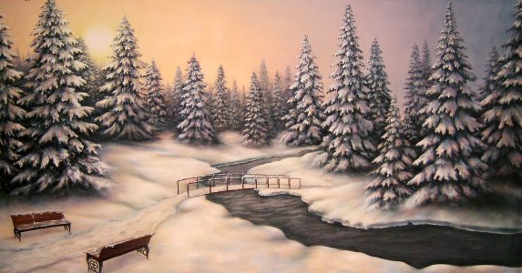 Snowy forest scene with tall pine trees, a winding river, and a small wooden bridge in winter.