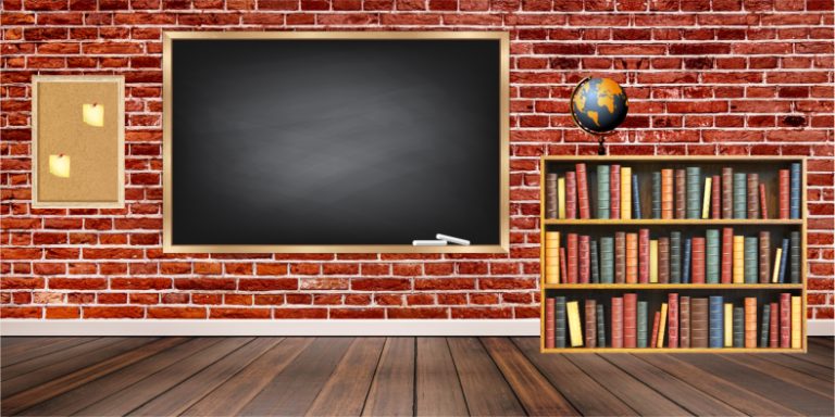 Brick-walled classroom with a large chalkboard, cork bulletin board with two candles, and a bookshelf topped with a globe.