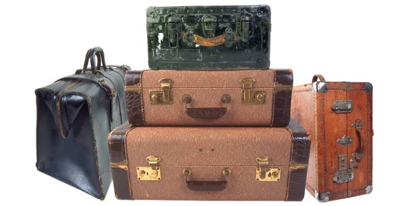 Stack of vintage suitcases in green, brown, and blue with brass hardware stacked against a white background.