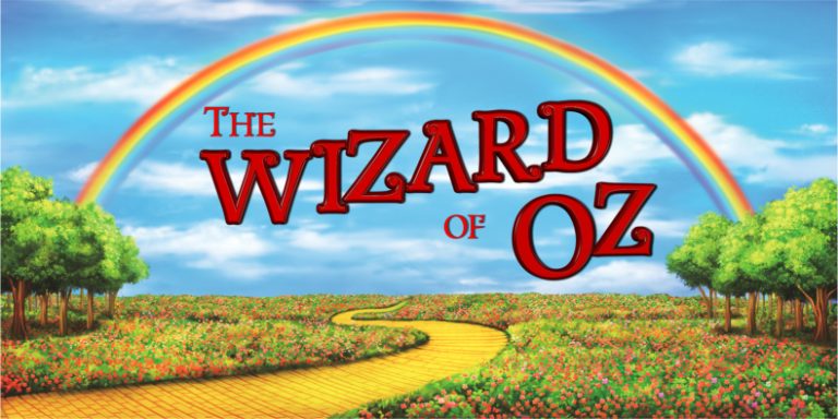 Poster for The Wizard of Oz featuring a bright rainbow arching across a blue sky, with a yellow brick road winding through a field of flowers toward the horizon and the red title text 'The Wizard of Oz' across the sky.